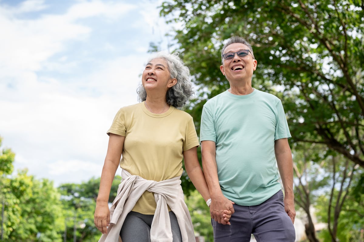 A mature couple walks together outdoors, relaxed and smiling